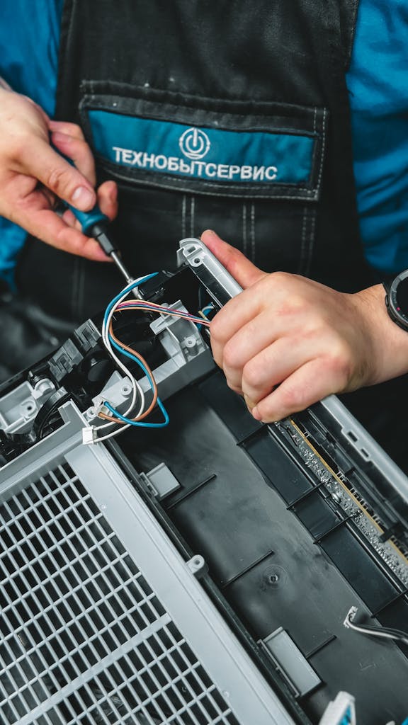Close-up of technician repairing a device, showcasing wiring and tools, ideal for tech and repair themes.